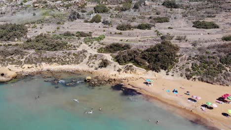 Ramla-Bay-Beach-En-Gozo,-Isla-De-Malta-Con-Gente-Nadando-Y-Disfrutando-Del-Día-De-Verano-De-Guerra