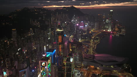 Bunte-Beleuchtung-Moderner-Wolkenkratzer-In-Der-Skyline-Der-Insel-Hong-Kong-Mit-Glühen-Am-Himmel