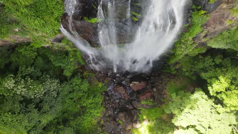 Water-cascading-down-towards-a-natural-rainforest-swimming-hole-deep-in-a-tropical-jungle-valley