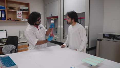 Indian-scientist-explaining-technical-scientific-prototype-device-in-collaboration-with-Arabic-team-member-in-research-laboratory