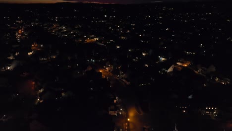 Aerial-tilt-up-reveal-of-houses-in-large,-sprawling-American-neighborhood-during-sunset,-dusk