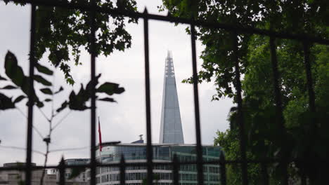 The-Shard-tallest-tower-in-London-UK,-ground-level-static-shot-through-steel-railings