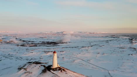 Reykjanesviti-Lighthouse-with-distant-Gunnehver-geothermal-area-in-Iceland,-winter-season