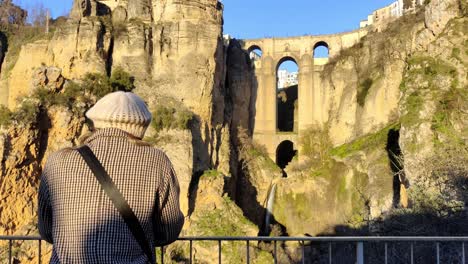 Rotating-shot-around-a-tourist-admiring-the-archways-at-Ronda,-Spain