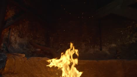 Fire-burning-in-a-stone-fireplace-in-slow-motion,-flame-rising