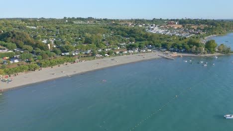 Boote-Und-Schwimmer-Spielen-Im-Meer-Neben-Einem-Riesigen-Campingplatz-Am-Strand