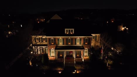 Aerial-descending-transition-shot-of-large-American-home-at-night