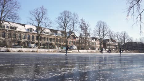 Dutch-locals-ice-skating-on-frozen-river-in-historic-Leiden-town,-Netherlands