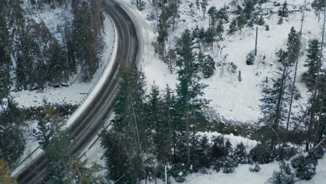 Aerial-View-Of-Road-In-Winter-Forest-During-Daytime---aerial-drone-shot