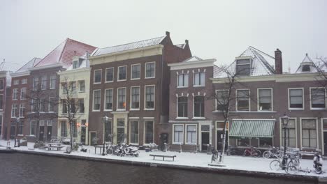 Leiden-city-buildings-in-winter-snow-on-Rijn-riverside,-Netherlands,-panoramic