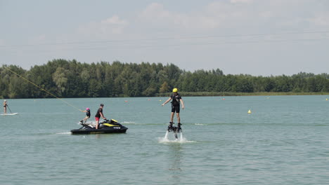 Wide-shot-of-flyboarder,-water-skier-and-person-on-stand-up-paddling-are-active-on-lake-in-summer