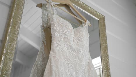 Wunderschönes-Hochzeitskleid,-Das-In-Einem-Golden-Gerahmten-Spiegel-In-Einem-Weißen-Raum-Hängt