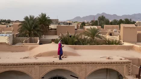 An-Asian-Middle-East-Girl-Wear-Scarf-and-Blue-Galaxy-Red-Pomegranate-Color-Shirt-Walking-on-Old-Historical-Ancient-Club-House-Made-by-Adobe-and-Mudbrick-by-Traditional-Architecture-Design-Iran-Yazd