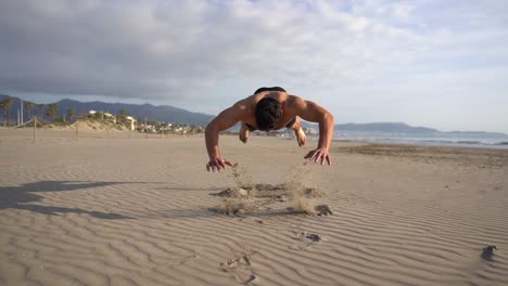 Muskulöser-Mann-Mit-Nacktem-Oberkörper,-Der-Push-ups-Variante-Mit-Sprung-Am-Strand-Durchführt