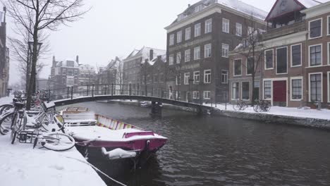 Rhine-river-flowing-through-snowy-Leiden-city-centre,-winter-Netherlands-city