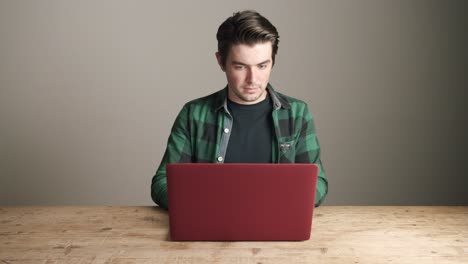 Young-caucasian-man-works-at-computer-laptop-on-grey-background