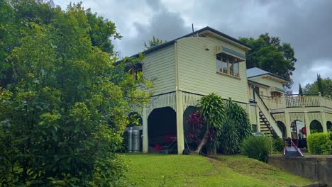 Smooth-slow-cinematic-reveal-shot-of-the-back-of-a-classic-traditional-country-Queenslander-house,-with-a-splendid-back-deck,-nestling-in-neatly-manicured-landscaped-garden