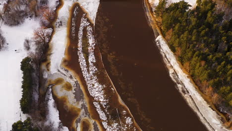 Ice-blocks-drifting-down-the-river-stream-in-spring-during-thaw,-aerial-zoom-out