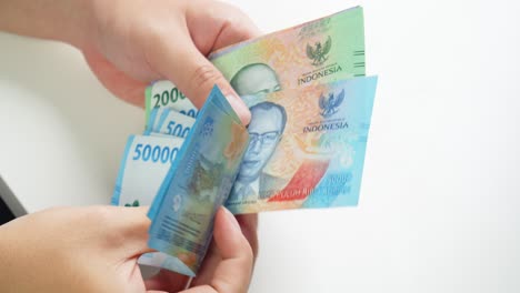 Contando-La-Rupia-Indonesia-Con-La-Mano-Manualmente,-Una-Pequeña-Cantidad-De-Salario-O-Salario