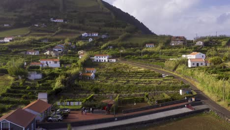 Drone-view-of-a-rural-village-with-crop-fields,-sunny,-cloudy-sky-in-Topo,-São-Jorge-island,-the-Azores,-Portugal