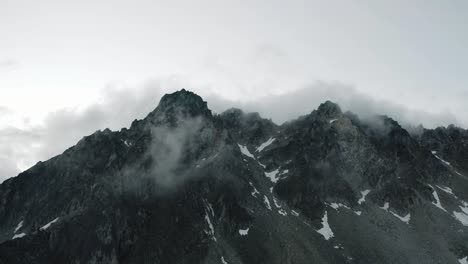Alaskische-Zerklüftete-Bergkette,-Drohne,-Die-Bei-Sonnenaufgang-Durch-Die-Wolken-Und-Berge-Fliegt