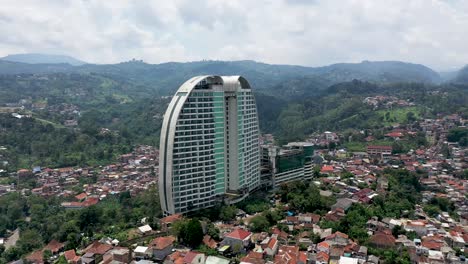 The-hotel-Maj-Meliá-Bandung-Dago-building-complex-with-tight-urban-homes-surrounding-it,-Aerial-dolly-out-shot