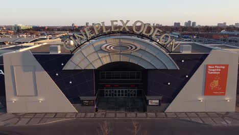 Aerial-reveal-of-Cineplex-Odeon-movie-theatre-cinema-exterior-signage-and-vacant-parking-lot