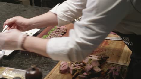 Chef-makes-plating-of-New-Zealand-meat-slices-on-wooden-cut-board-at-meat-tasting-event