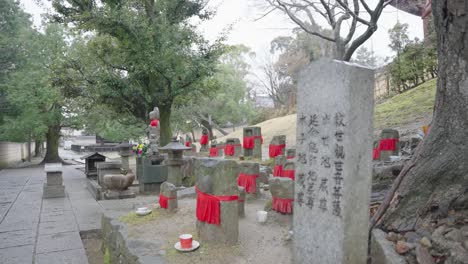 Jizo-Guardian-Statues-and-tombstone,-Rack-Focus-Reveal-Shot