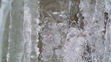 Kristallklare-Eiszapfen-Am-Wasserfall-Im-Winter,-Nahaufnahme-Schwenkschuss