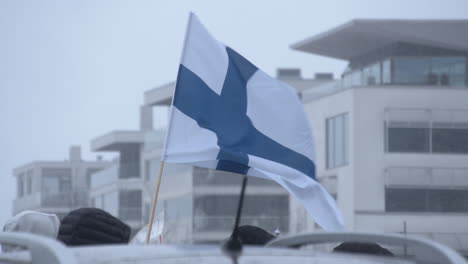 Closeup-shot-of-the-Finland-national-flag-blowing-in-the-wind-at-a-protest-on-Helsinki-over-covid-restrictions,-cold-snowy-day
