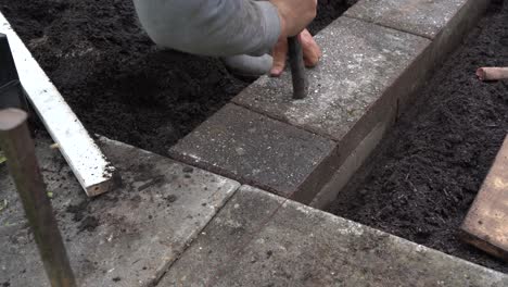 Bricklayer-Tapping-Bricks-Into-Place-To-Finish-Garden-Flower-Bed-Wall
