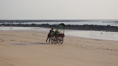 Juice-vendor-on-empty-beach-in-Mumbai-looking-for-a-customers-|-Juice-vendor-moving-with-his-stall-on-empty-beach-in-Mumbai,-15th-March-2021