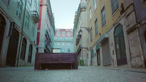 Empty-Lisbon-city-downtown-with-public-bench,-old-buildings-facade-during-covid-19-lockdown-at-sunrise-4k