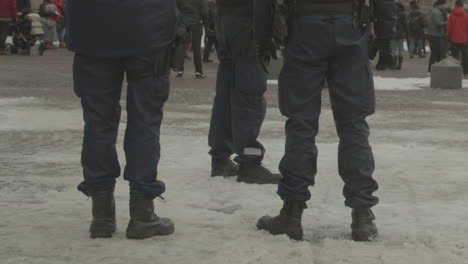 Low-shot-of-the-legs-and-boots-of-police-officers-standing-on-snowy-street-on-a-cold-winter-day