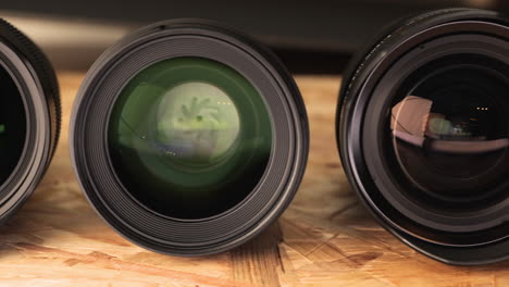 Various-Camera-Lenses-With-Reflections-Lined-On-Wooden-Table