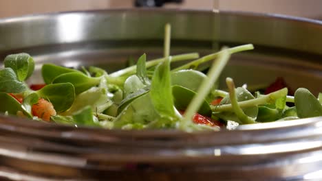 Pouring-extra-virgin-olive-oil-on-freshly-chopped-salad-in-close-up-view