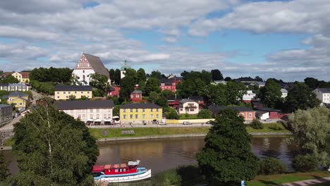 Aerial-panning-shot-of-idyllic-Porvoo-City-with-colorful-houses,Porvoonjoki-river-and-docking-boat-during-sunny-day,Finland