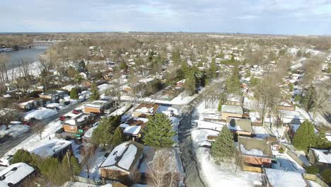 Slow-moving-Aerial-Shot-of-these-urban-streets,-houses-and-trees-covered-by-snow