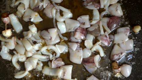 overhead-view-of-cuttlefish-with-garlic-on-friendose-paellon-in-olive-oil-in-slow-motion