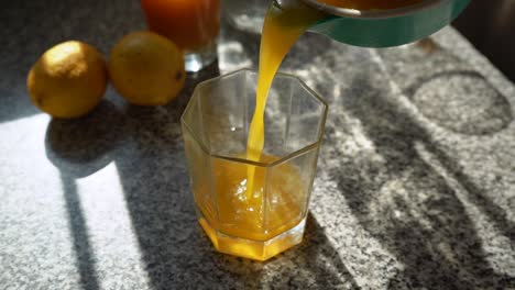 Pouring-Fresh-Squeezed-Orange-Juice-Into-The-Empty-Clear-Glass---static,-low-angle-shot