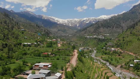 Antena-Sobre-Carretera-A-Través-Del-Valle-Swat-Con-Montañas-Cubiertas-De-Nieve-En-La-Distancia