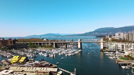 City-Aerial-Pass-Over-Harbor-with-Boats-in-Front-of-Scenic-Mountain-Landscape---Slow-Motion