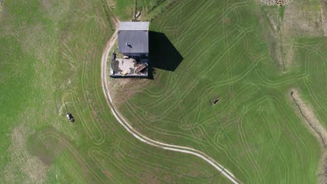 Top-down-aerial-view,-Mountain-farmer-tills-his-field-with-tractor-and-hose