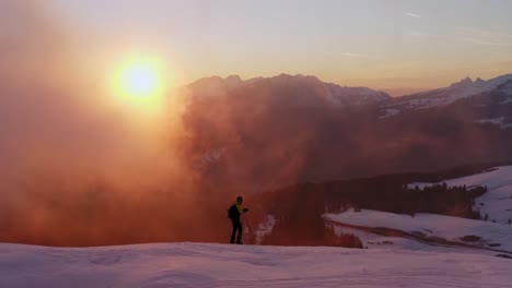 Aerial-view-of-hiker-with-ski-walking-on-snowy-Dolomites-mountain-ridge-at-sunset