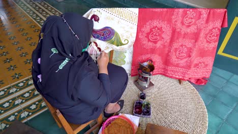 Rear-view-of-Muslim-woman-creating-unique-batik-motif-on-fabric-using-melted-wax