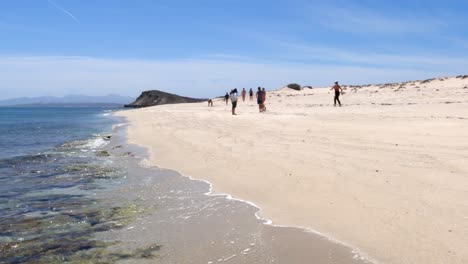 People-walk-along-a-beautiful-white-sand-beach-on-a-deserted-island-on-a-hot-sunny-day