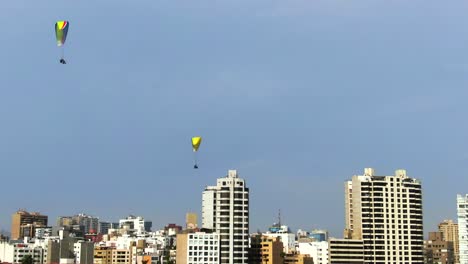 4K-Luftbild-Tagsüber-Von-2-Gleitschirmfliegern,-Die-über-Die-Küstenseite-Von-Lima-In-Miraflores,-Peru,-Fliegen