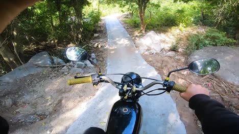 Pov-view-shot-of-motorcyclist-driving-on-narrow-rocky-path-in-surrounded-by-idyllic-nature-landscape-of-Vietnam