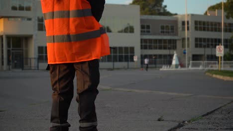 Cropped-Image-Of-A-Security-Personnel-In-Orange-Hi-Vis-Watching-A-Kid-Playing-Football-Outdoor